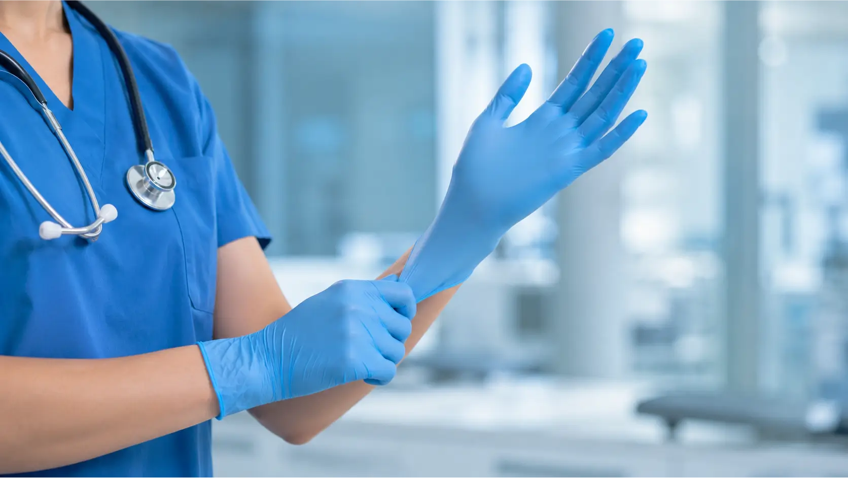 Healthcare Professional Putting on Nitrile Medical Gloves Healthcare professional putting on blue nitrile medical gloves in a clinical setting