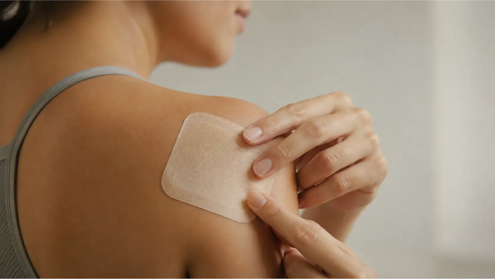 Therapeutic Pain Relief Patch Applied to the Shoulder Woman applying a therapeutic pain relief patch to her shoulder